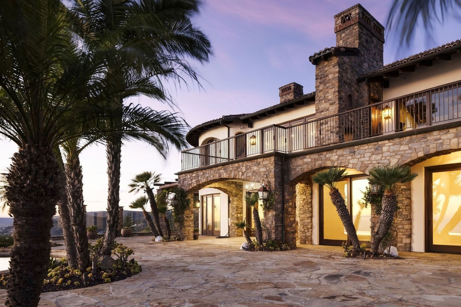 Covered and open terraces extend the living spaces toward the coastline, wrapping along the back of the home beneath the upper balconies.