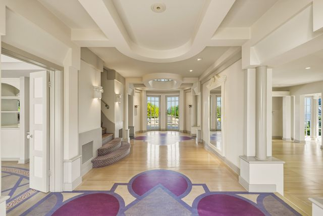 A formal center-hall foyer with wood floors and bold geometric inlays.