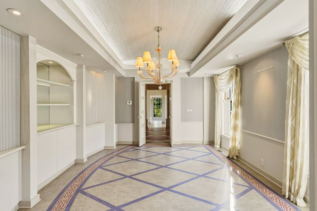 The formal dining room is set atop a patterned purple, pink, and grey floor.