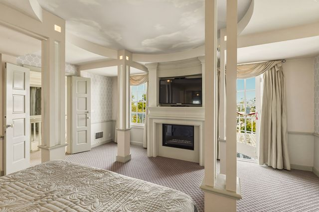 Multiple windows and a private balcony look out over the yard, just past the fireplace and built-in display areas.