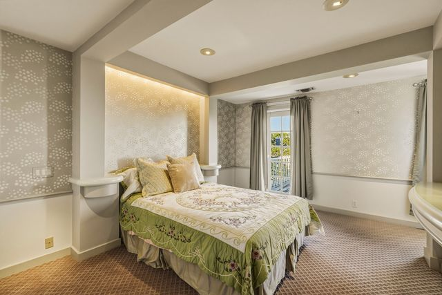 The secondary suite is a slightly smaller space with soft patterned wallpaper and a small balcony right off the bedroom.