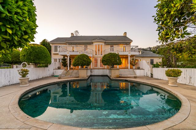 From the upper terraces, the property steps down to a circular pool bordered by topiary trees and white fencing.
