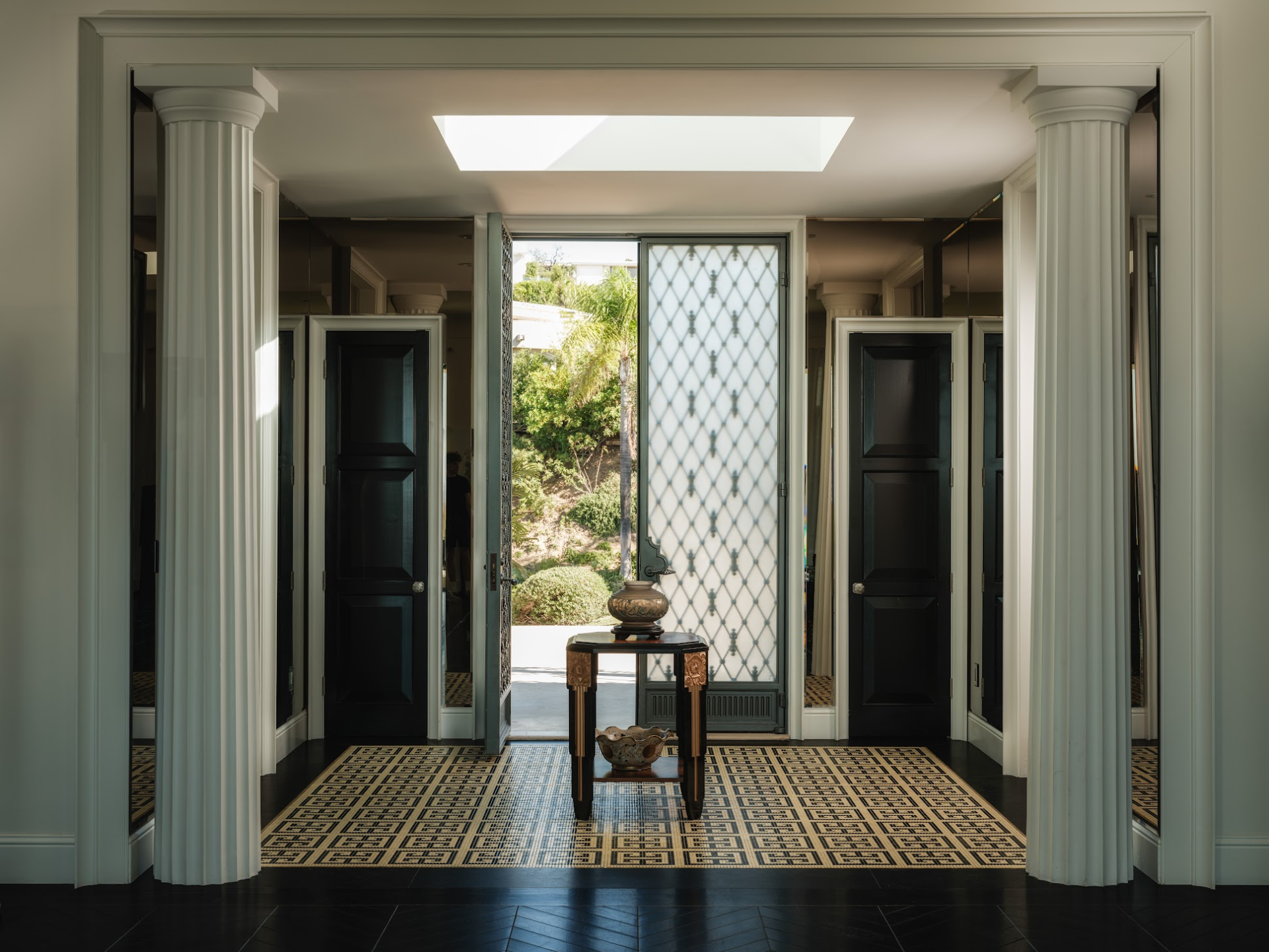Stepping through the front door, the home opens to a formal foyer framed by fluted columns and mirrored walls.