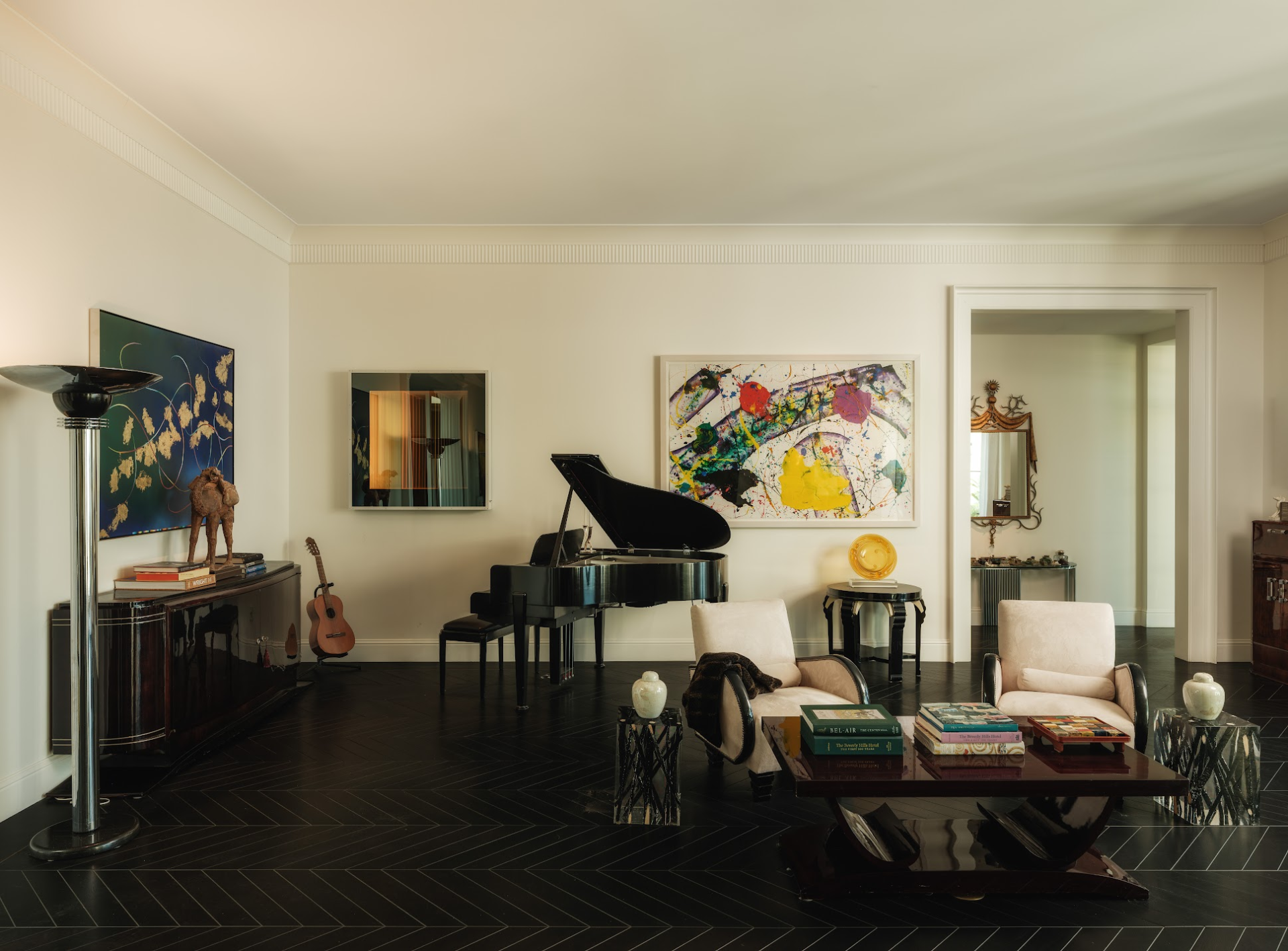 Living room arranged more loosely around a grand piano, reading chairs, and art-lined walls.