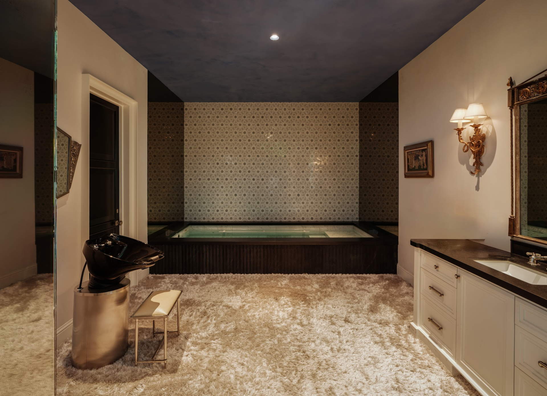 Bathroom with an indoor plunge pool set into a dark-paneled bathing area alongside a vanity and salon-style wash station.