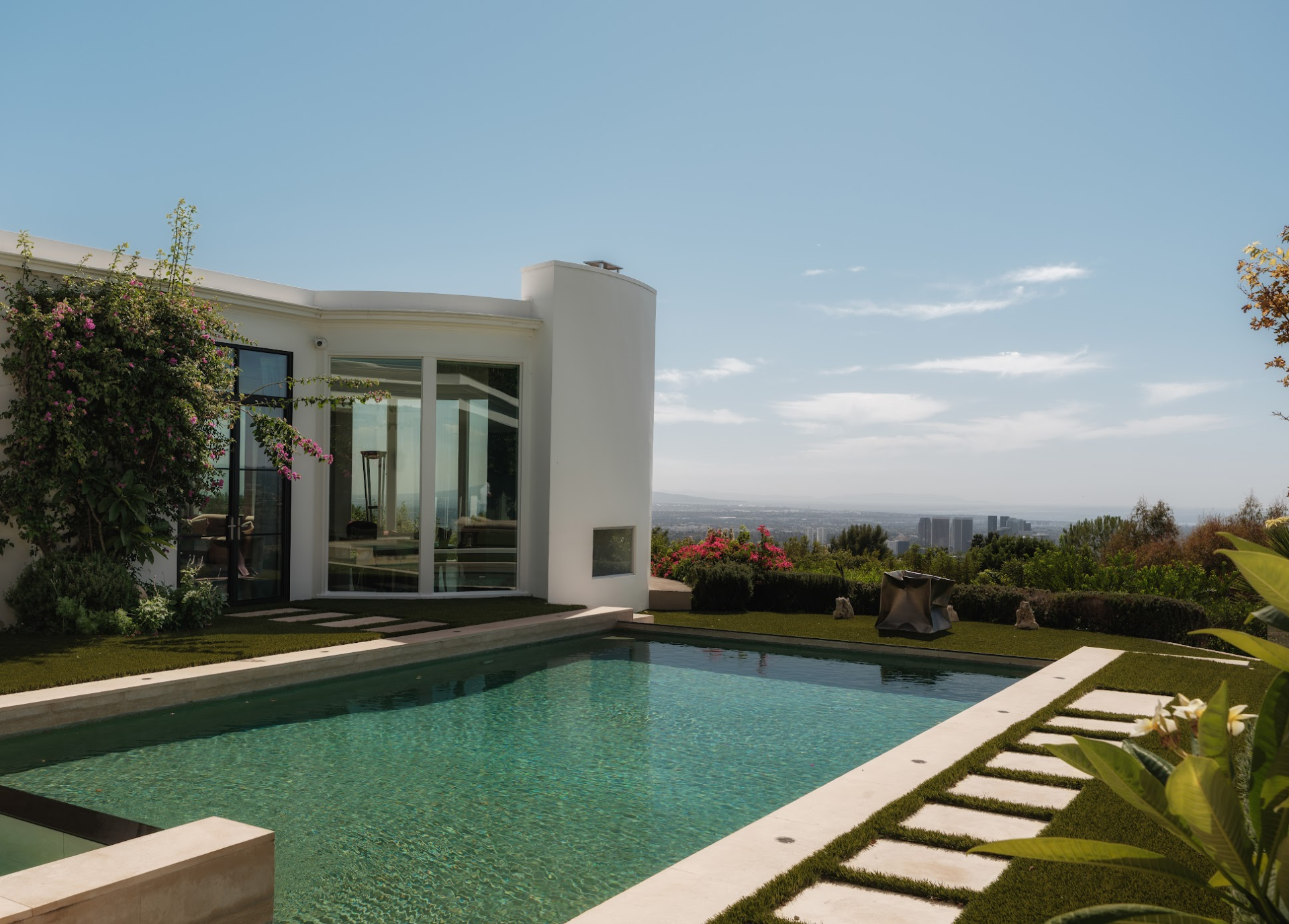 At the center of the backyard, an infinity-edge swimming pool looks across the Los Angeles skyline.