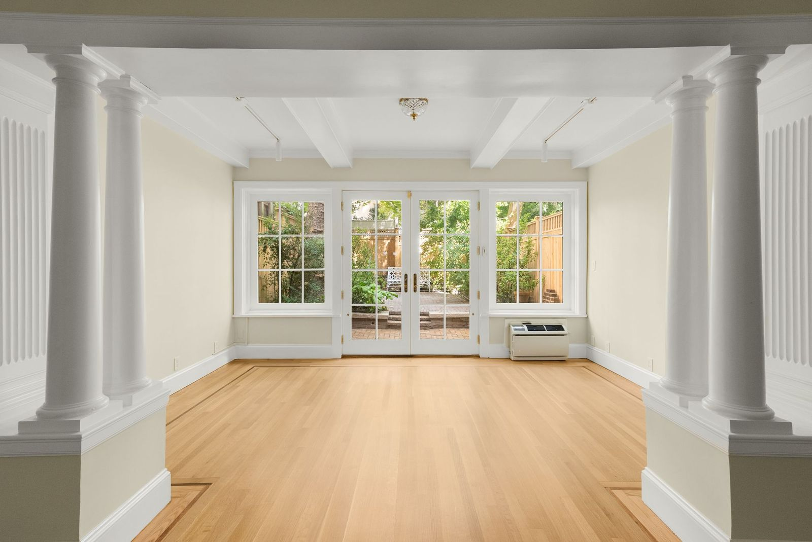 The den stretches toward the back of the townhouse, where glass doors and matching windows open directly to the garden and bring natural light across the hardwood floors.