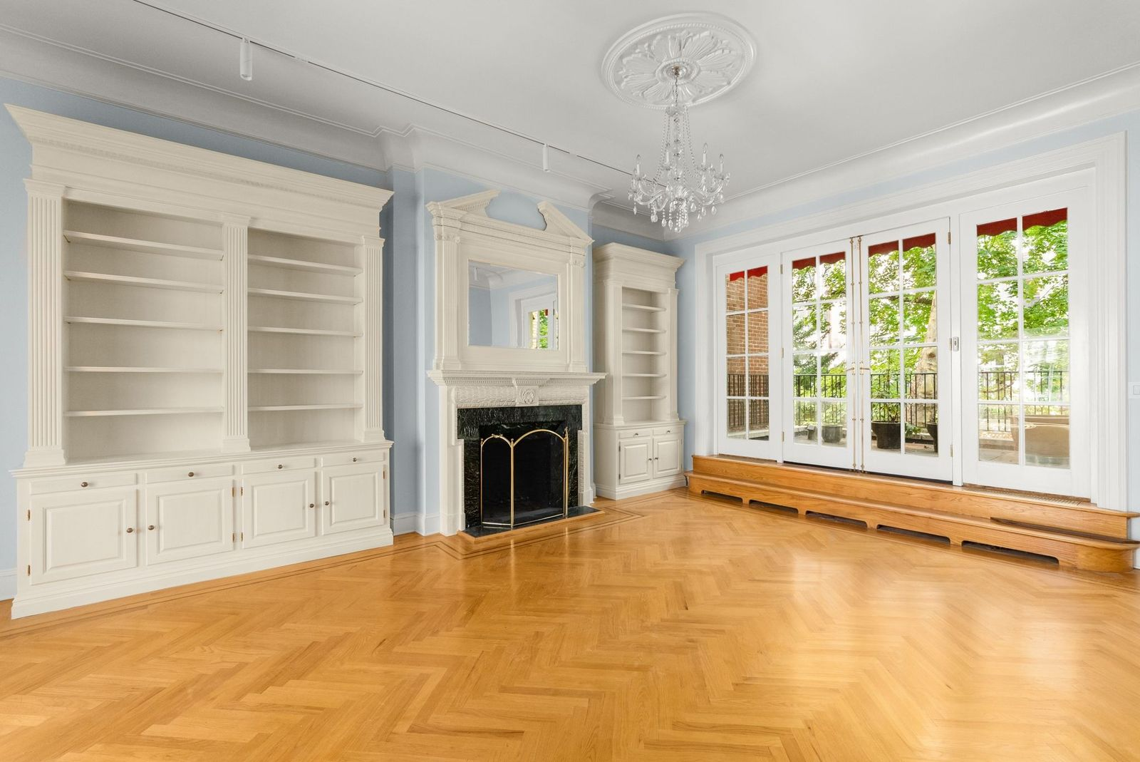 A larger sitting area with its own fireplace framed by built-in shelving and cabinetry. 