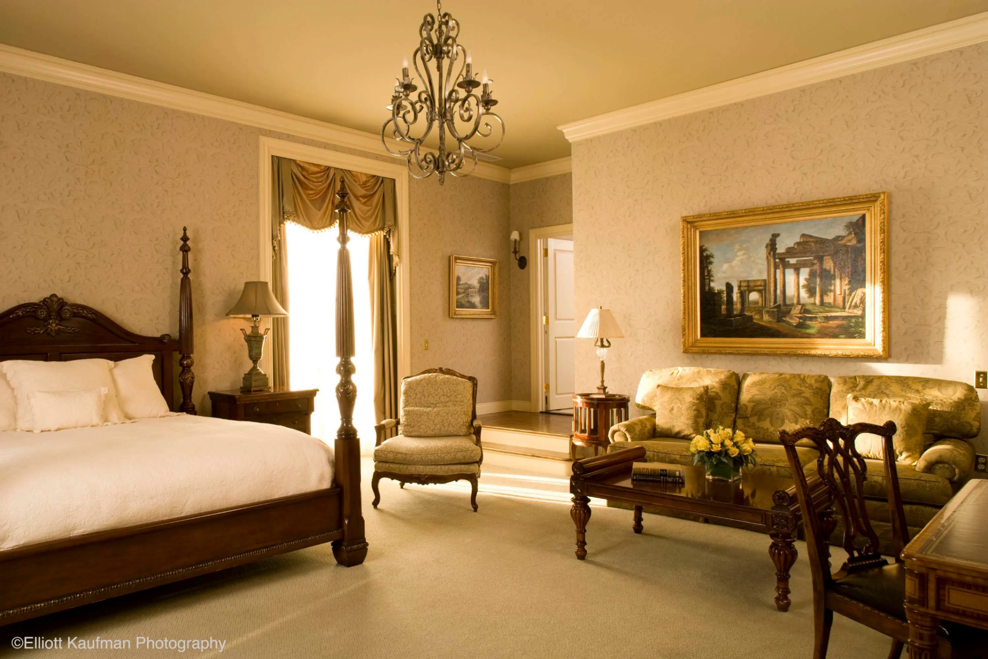 A second suite has a more formal design, with patterned wallpaper, layered curtains, and a silver-metal chandelier.