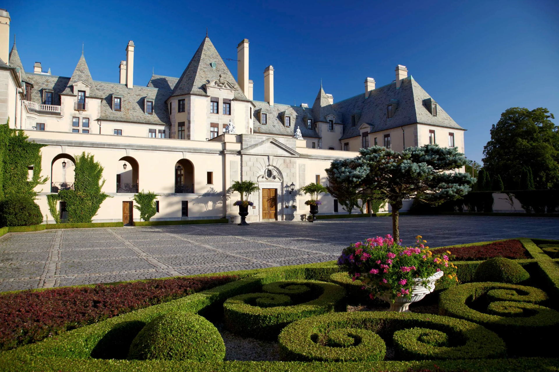 The formal grounds begin close to the mansion with flower beds and tightly shaped hedges framing a stone courtyard.