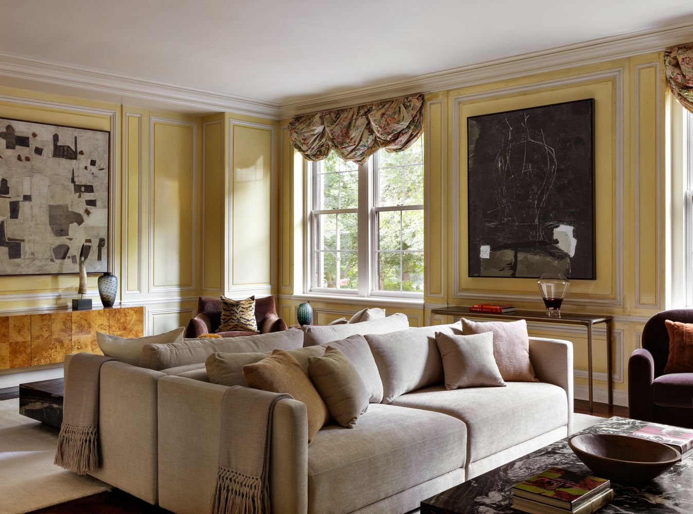 A pair of back-to-back sofas fills the middle of the room, while darker armchairs are set closer to the windows.