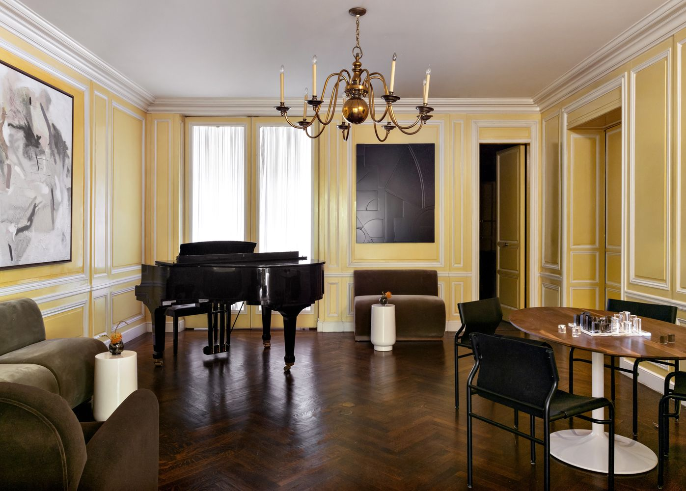 A grand piano sits in the corner to face a variety of chairs and a round game table.