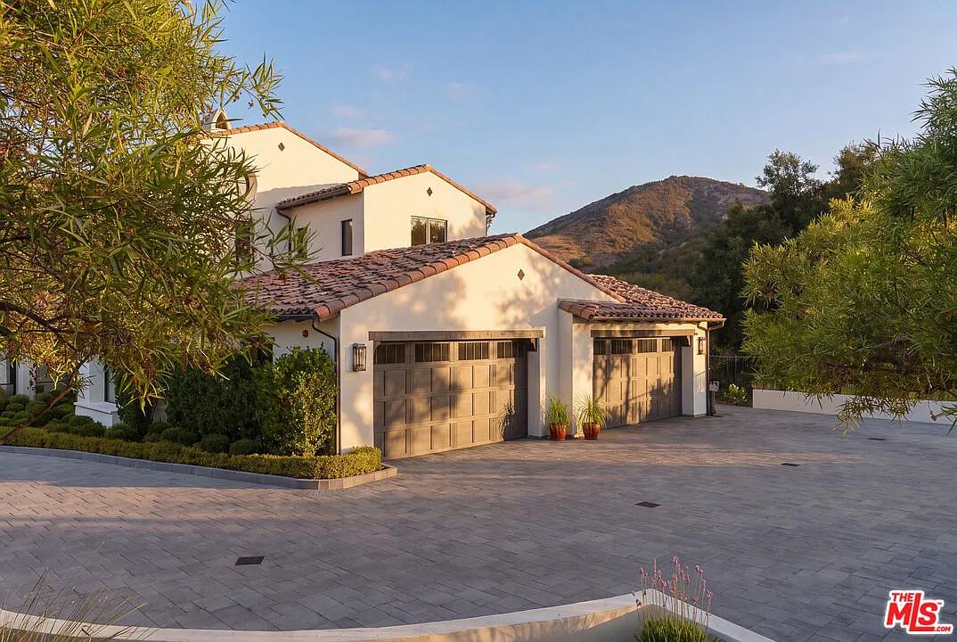 A wider motor gate opens to the paved driveway and multi-car garage.