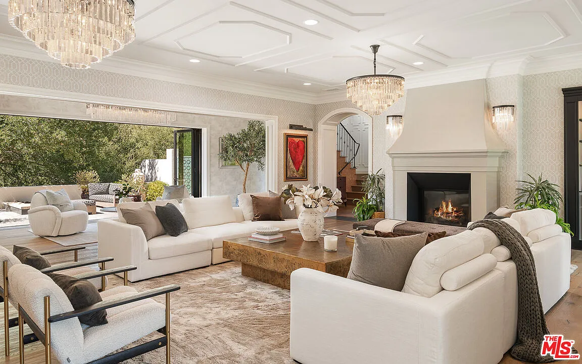 A central seating area beneath a coffered ceiling, with a fireplace set along one wall and sofas arranged around a low wood coffee table.