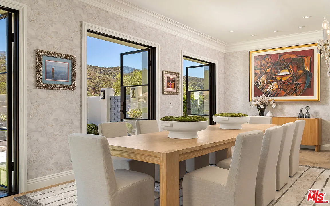 The formal dining room opens toward the front of the house through a series of tall black-framed glass doors.