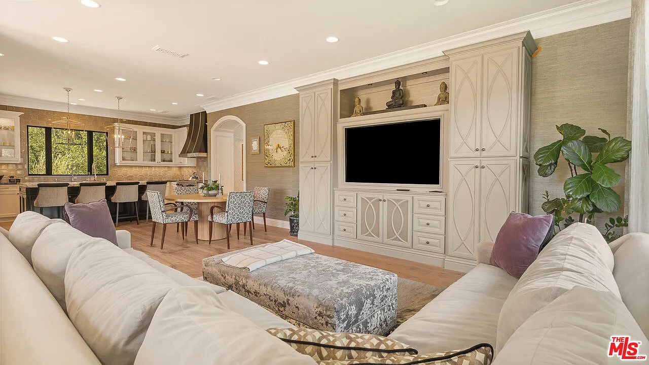The family room has an L-shaped sofa facing a full wall of custom cabinetry that frames the mounted TV.