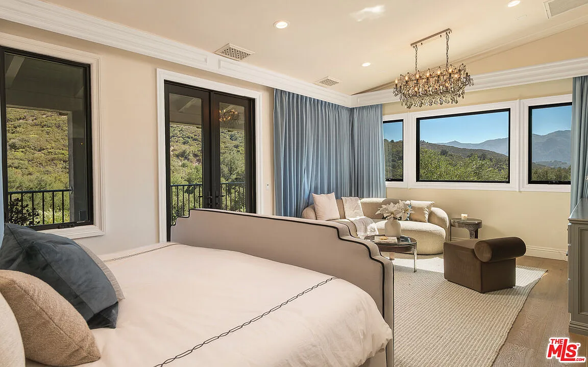 The primary suite is centered around a long vertical bedroom that opens directly to its own balcony overlooking the surrounding hills.