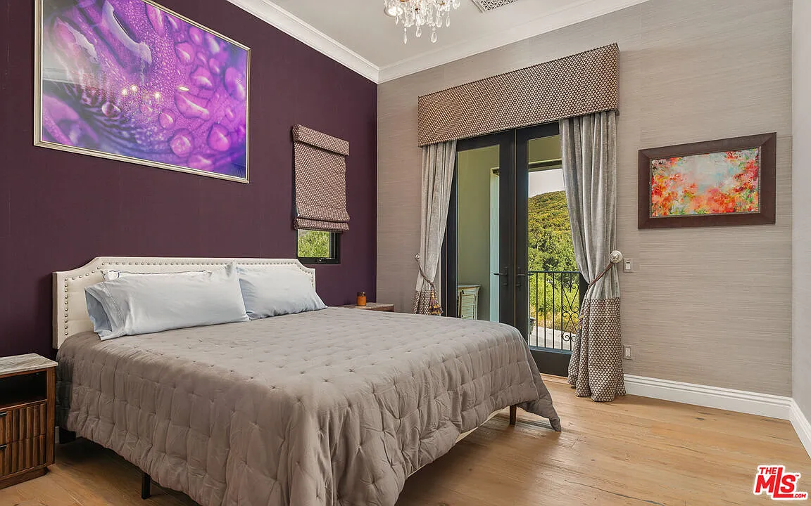 The second suite has a darker palette, with a deep plum accent wall behind the bed and gray wallpaper wrapping the rest of the room and balcony doors.