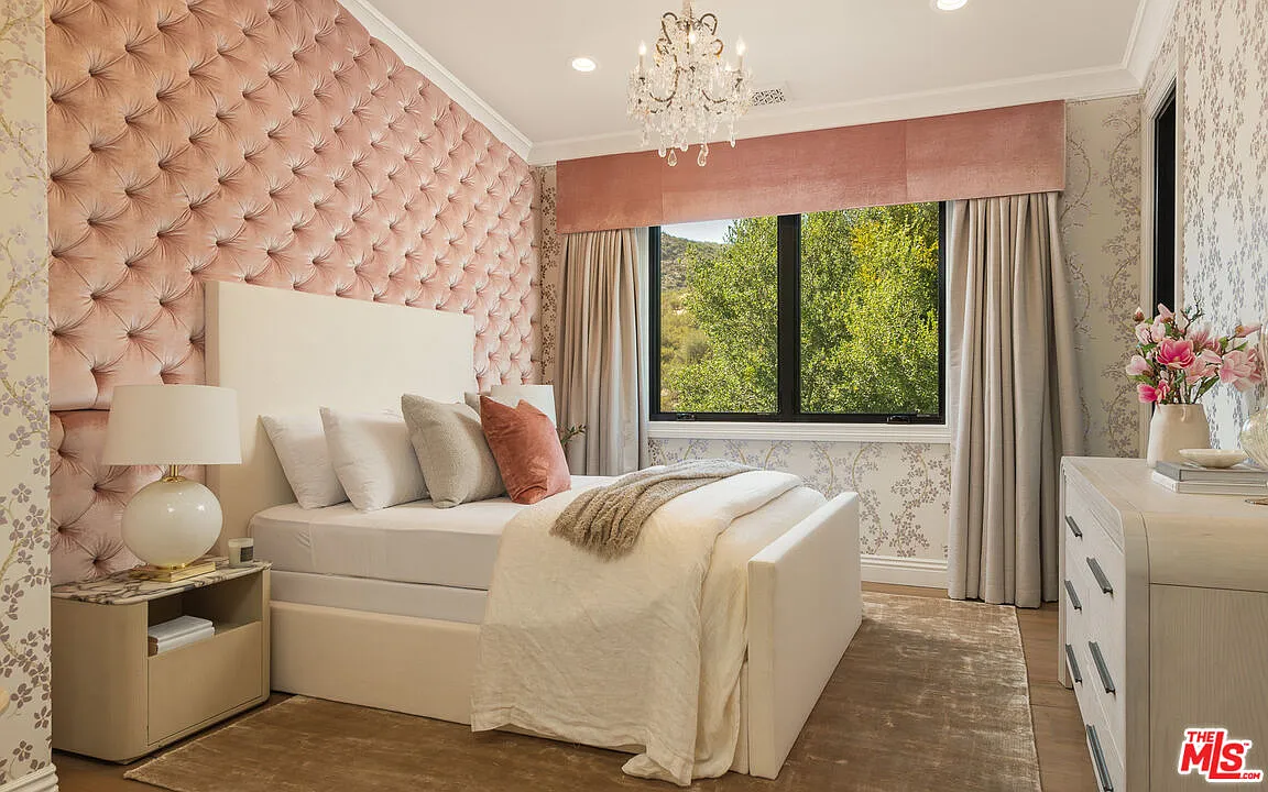 The third bedroom has the softest look of the three, with patterned flower walls and a tall tufted pink accent wall rising behind the bed.