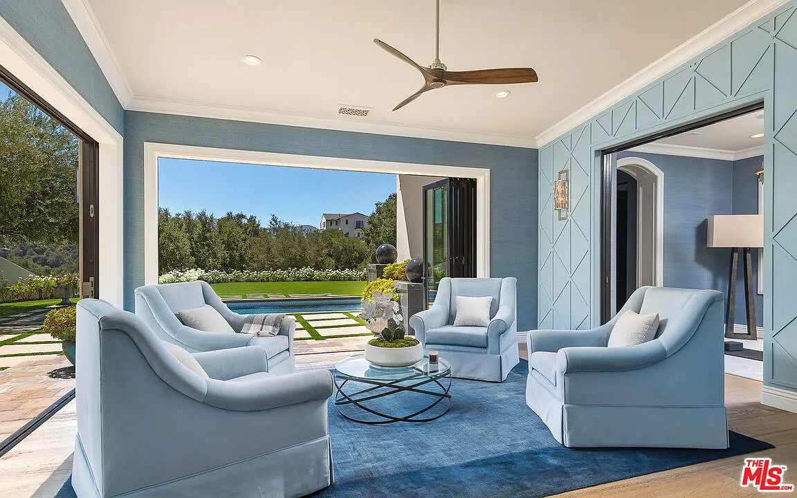 The sunroom opens through wide folding glass doors, creating a sheltered transition before stepping outside.